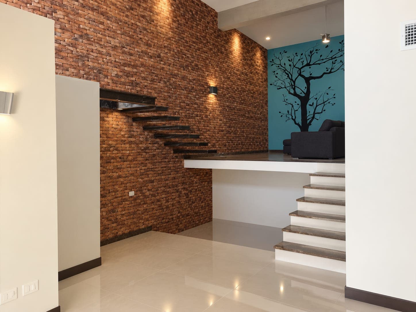 Escalera flotante sobre muro de ladrillo y desnivel hacia la estancia de Casa Armonía