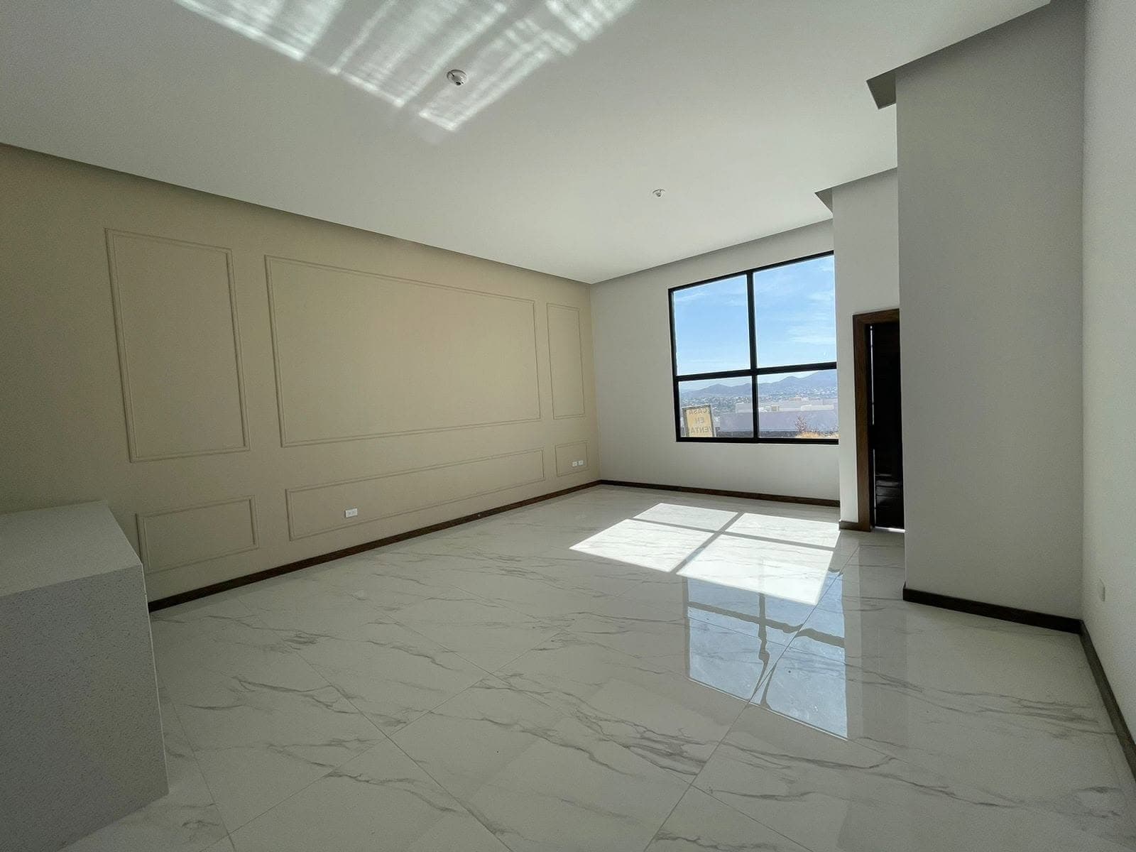 Sala de Casa Aurora con muro de molduras y ventanal con vista a la sierra