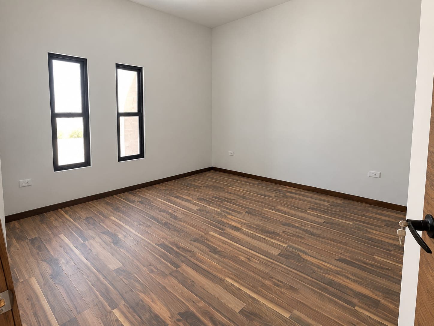 Recámara de Casa Aurora con piso de madera y dos ventanas verticales